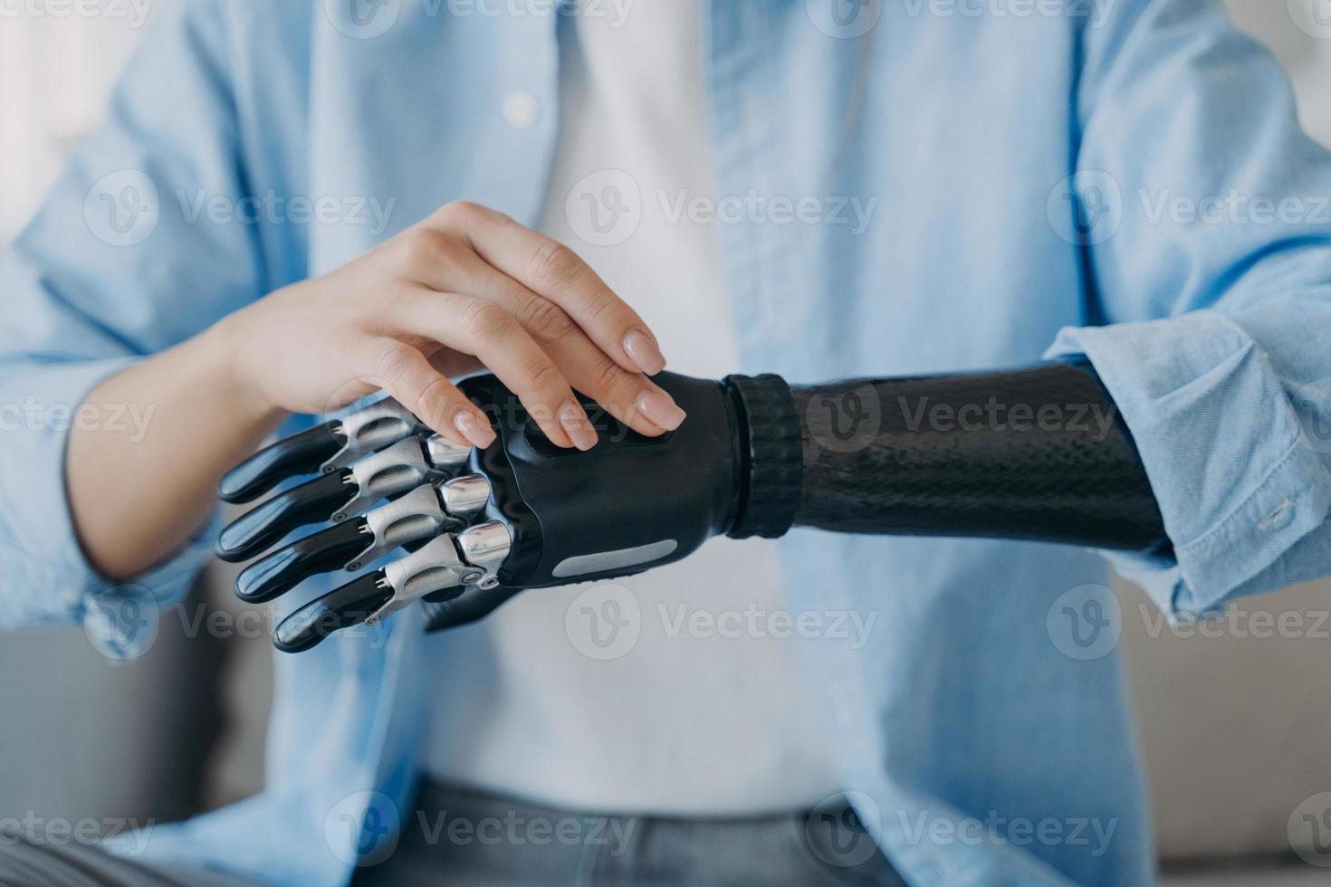 Cyber hand of female amputee. Disabled woman is changing settings of robotic prosthesis. photo