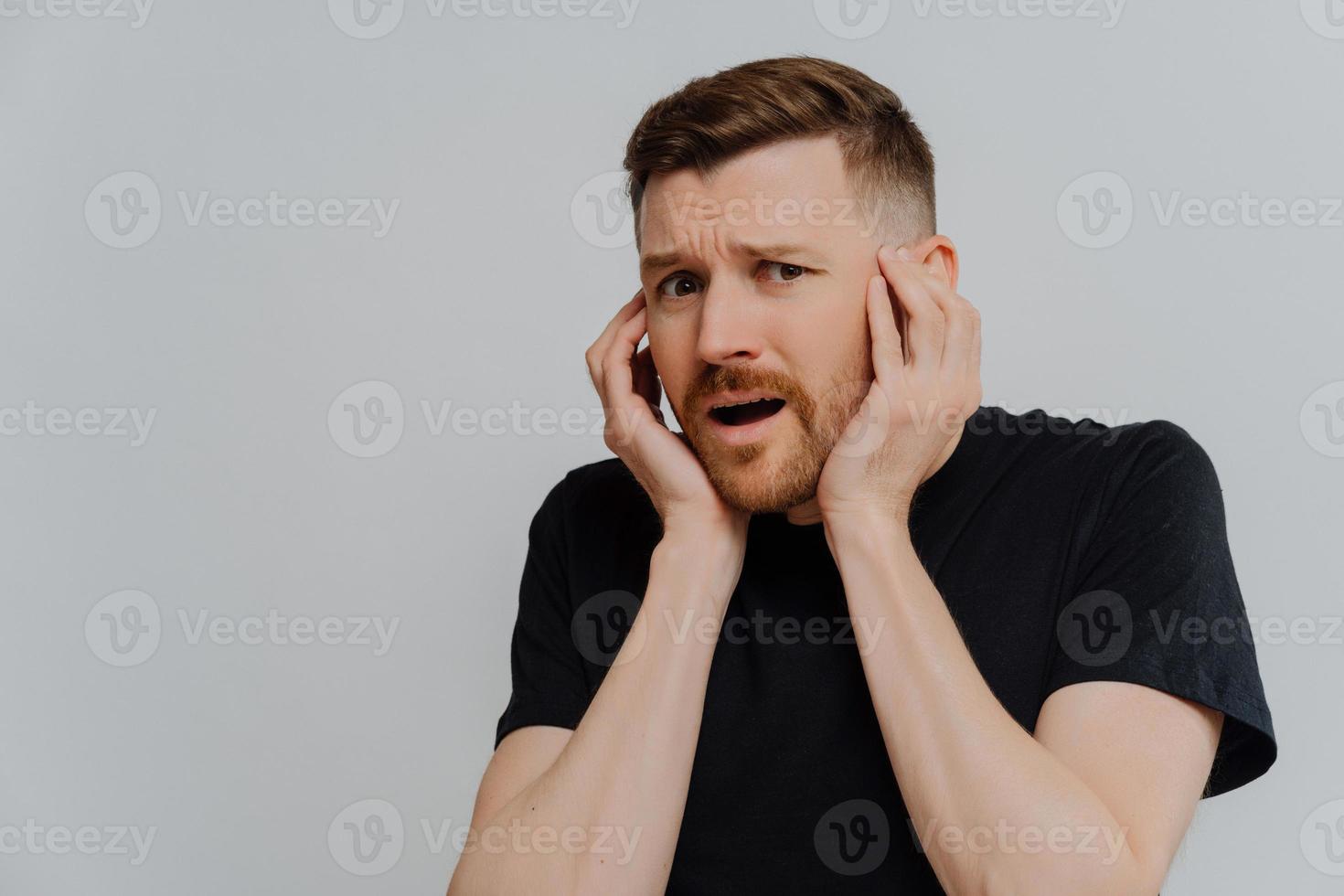 Shocked scared man looking at camera with frightened face expression photo