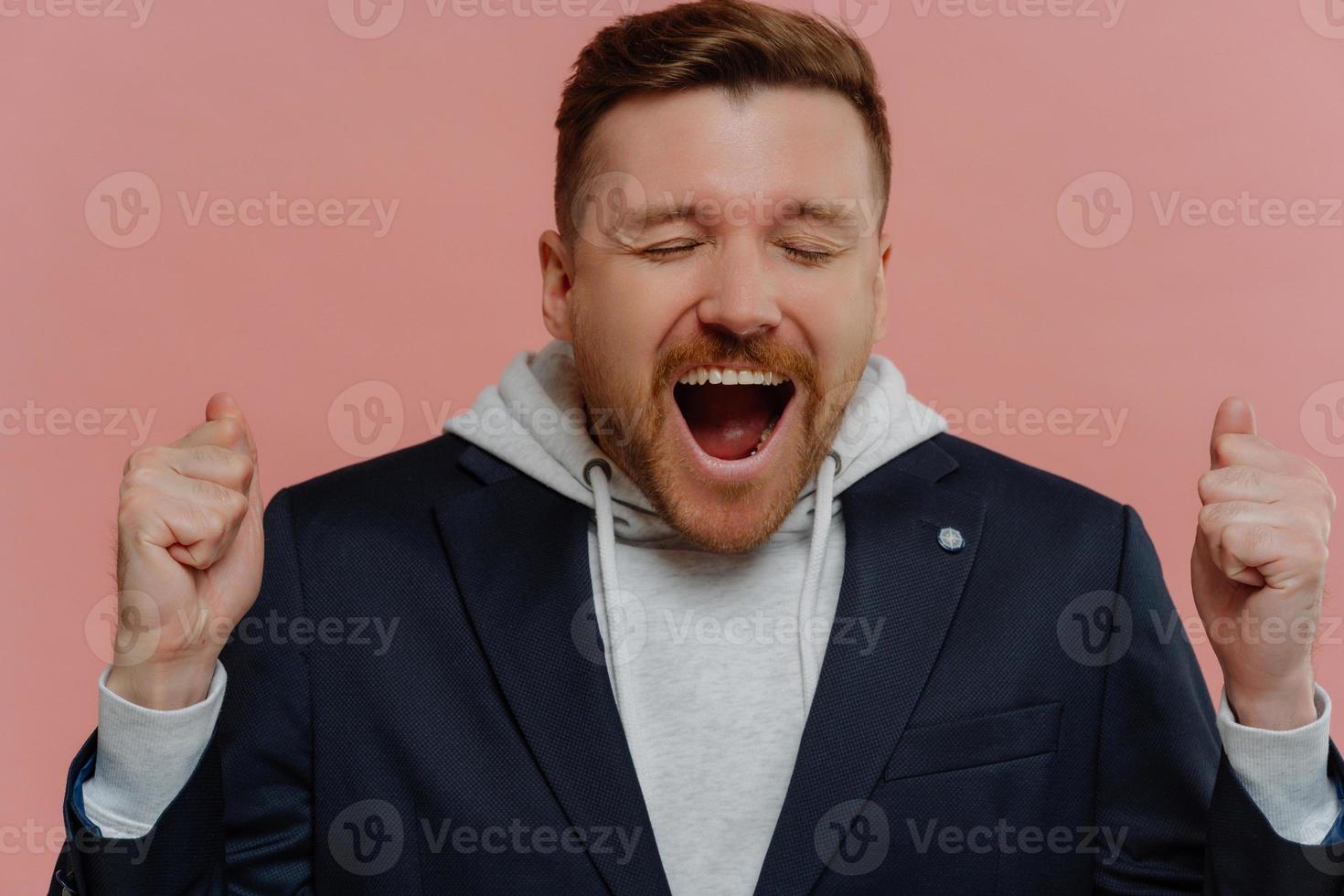 Overjoyed man with clenched fists and closed eyes celebrating victory photo