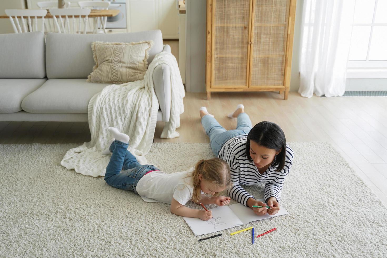 Mañana de fin de semana en familia. mamá y niño tirados en el suelo juntos y pintando con marcadores de colores. foto