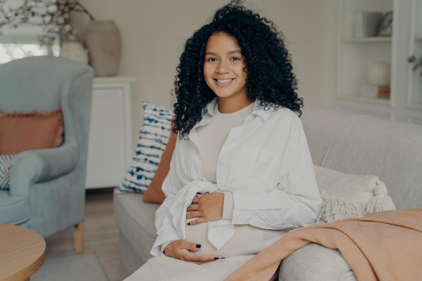 Cute mixed race pregnant lady with curly hair enjoying wonderful time of pregnancy photo