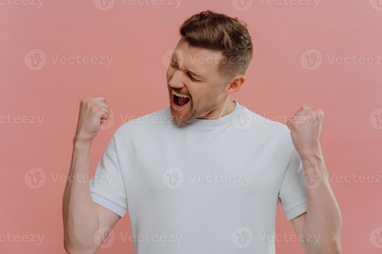 Young excited man in white blank tshirt celebrating success photo