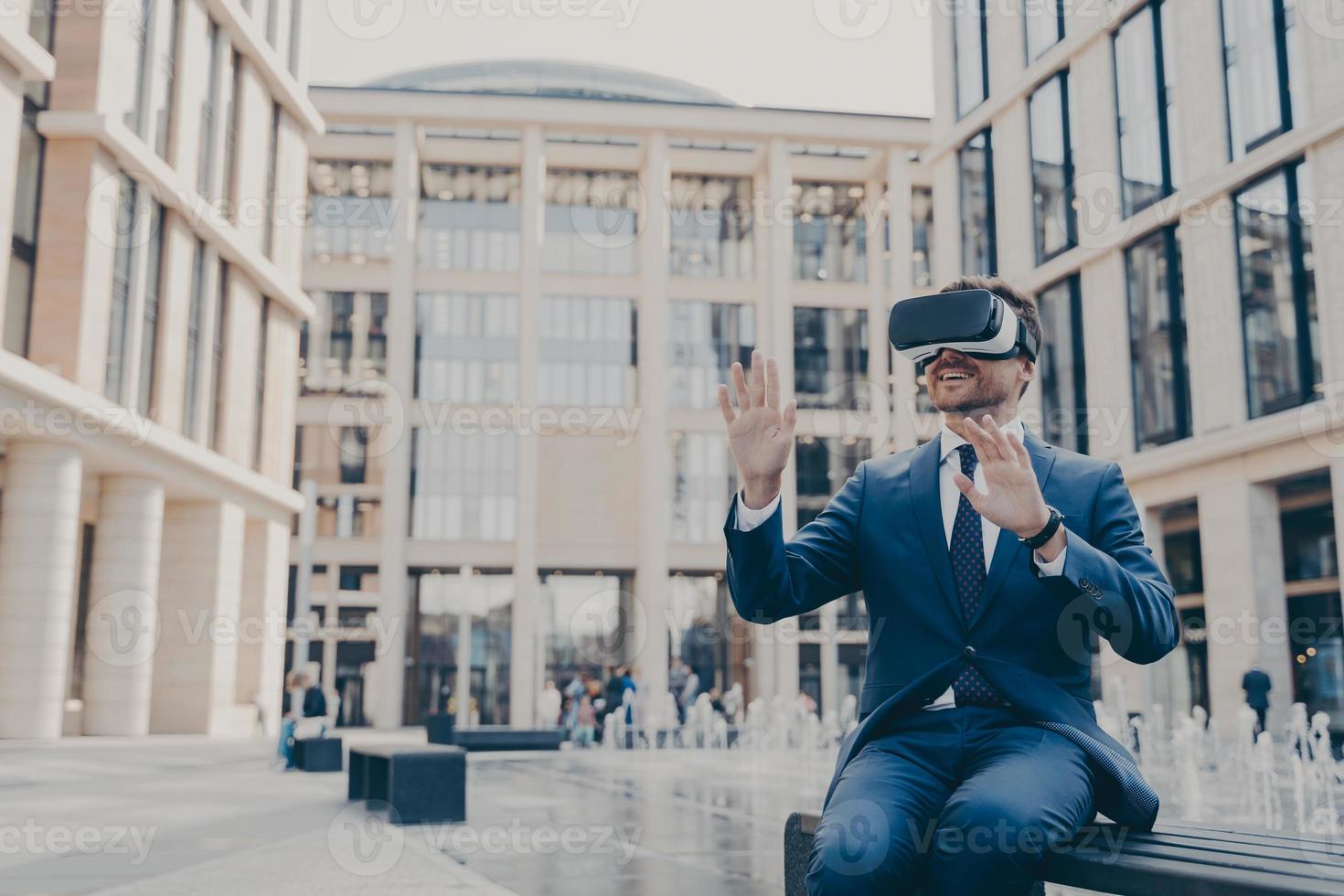 Impressed young businessman or office worker testing virtual reality goggles, using VR headset photo