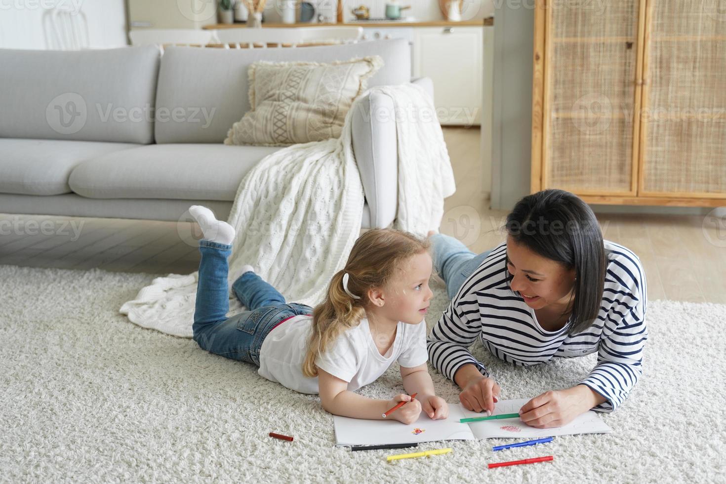 Little daughter and mother drawing painting lying together on floor. Educational pastime, creativity photo