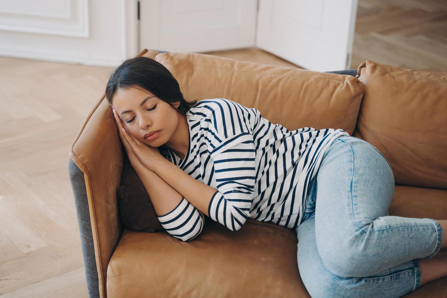 Tired female lying on sofa sleeping takes day nap after sleepless night at home. Fatigue, lazy time photo