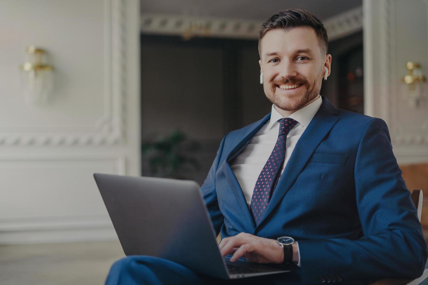 Happy man executive manager looking happy and satisfied with business results while working with laptop in office photo