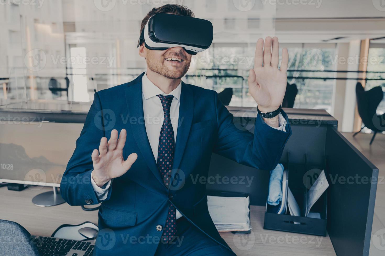 Excited entrepreneur in virtual reality glasses touching objects interact with 3D simulation photo