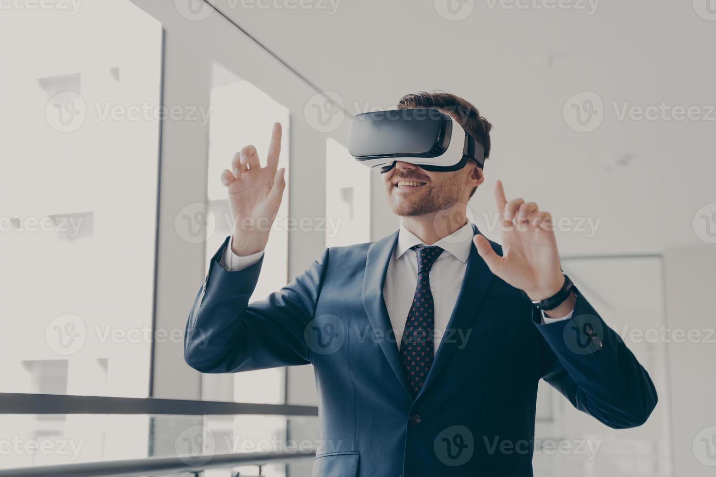 Excited office worker in vr headset or virtual reality goggles gesturing with hands photo