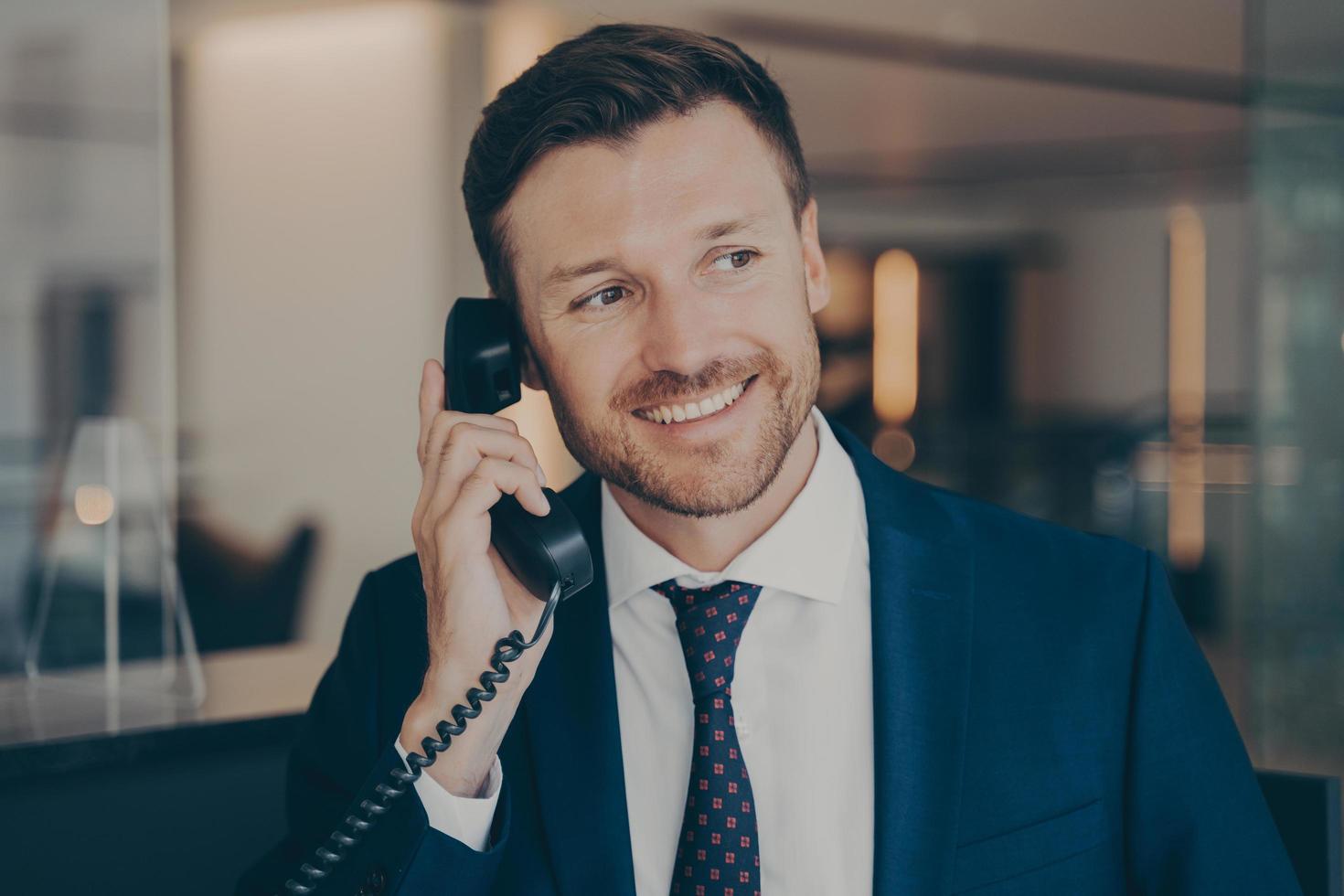 Satisfied male office worker calling his wife to notify her about promotion photo