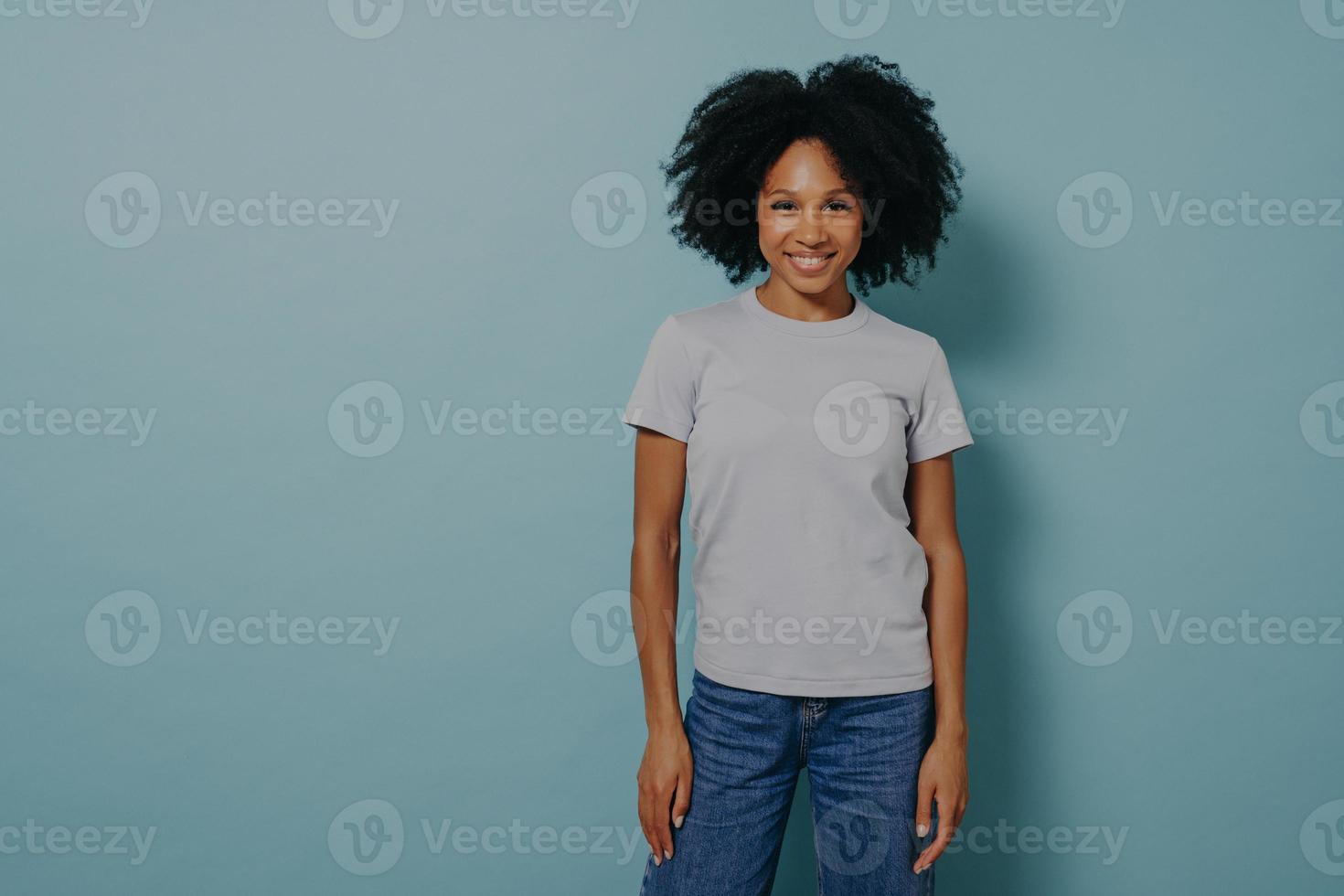 Delighted young african female posing isolated over blue background with pleasant smile photo