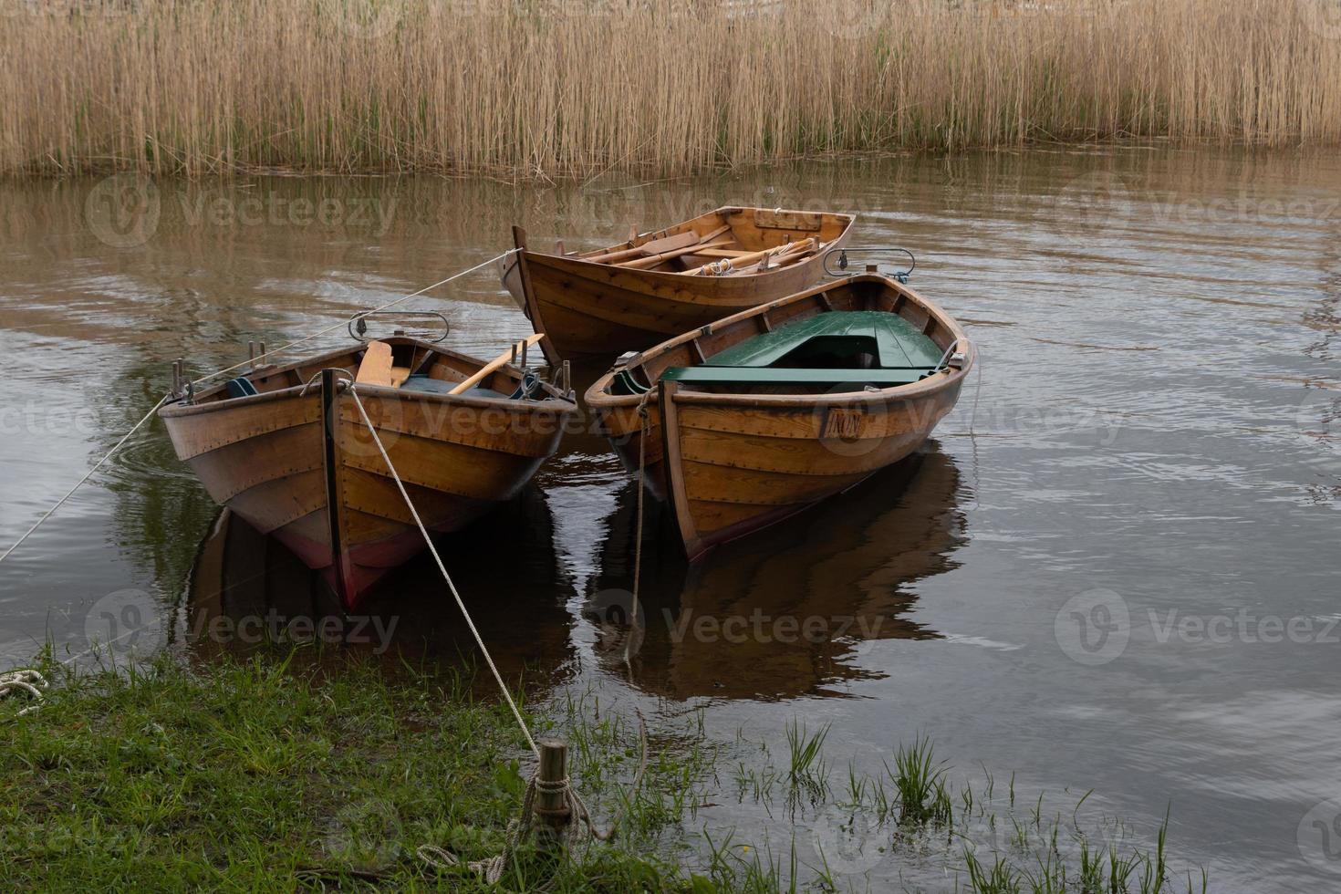 tres botes de remos de madera se balancean en el agua. foto