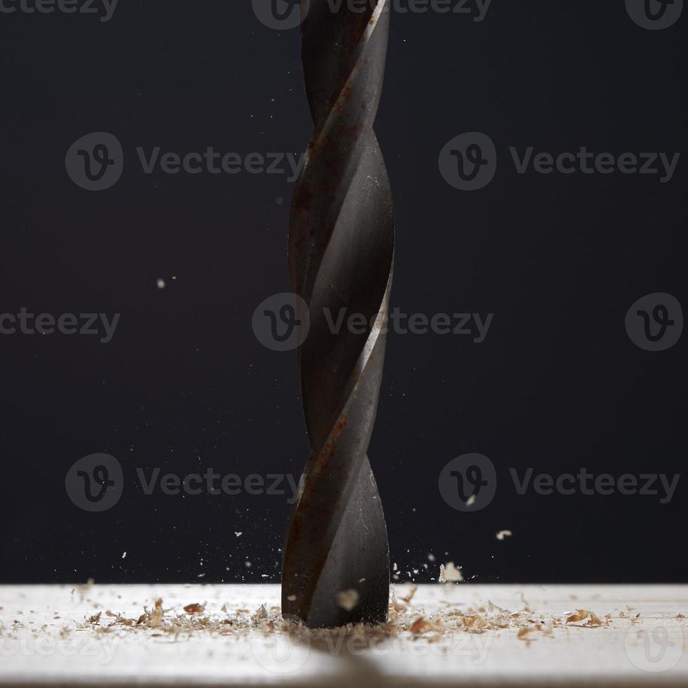 Wood drill bit with shaving on a gray background. Photo with copy space. Background in blur.