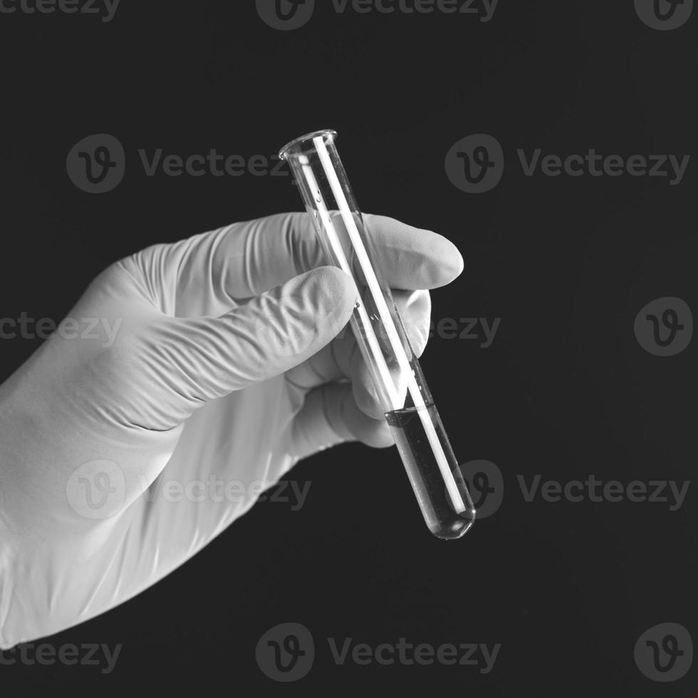 Hand holding liquid in test tube close up isolated on black background. photo