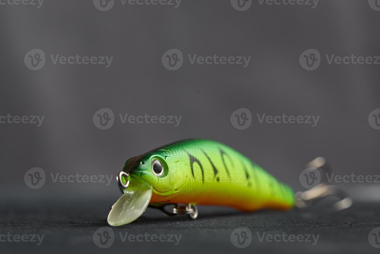 Fishing lure green used Wobbler closeup on gray background. Hooks and background in blur. photo