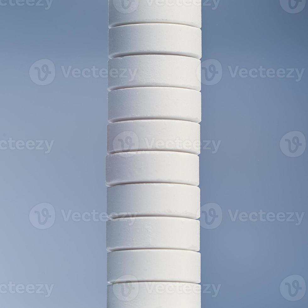 Stack of white capsules isolated on gray background. photo