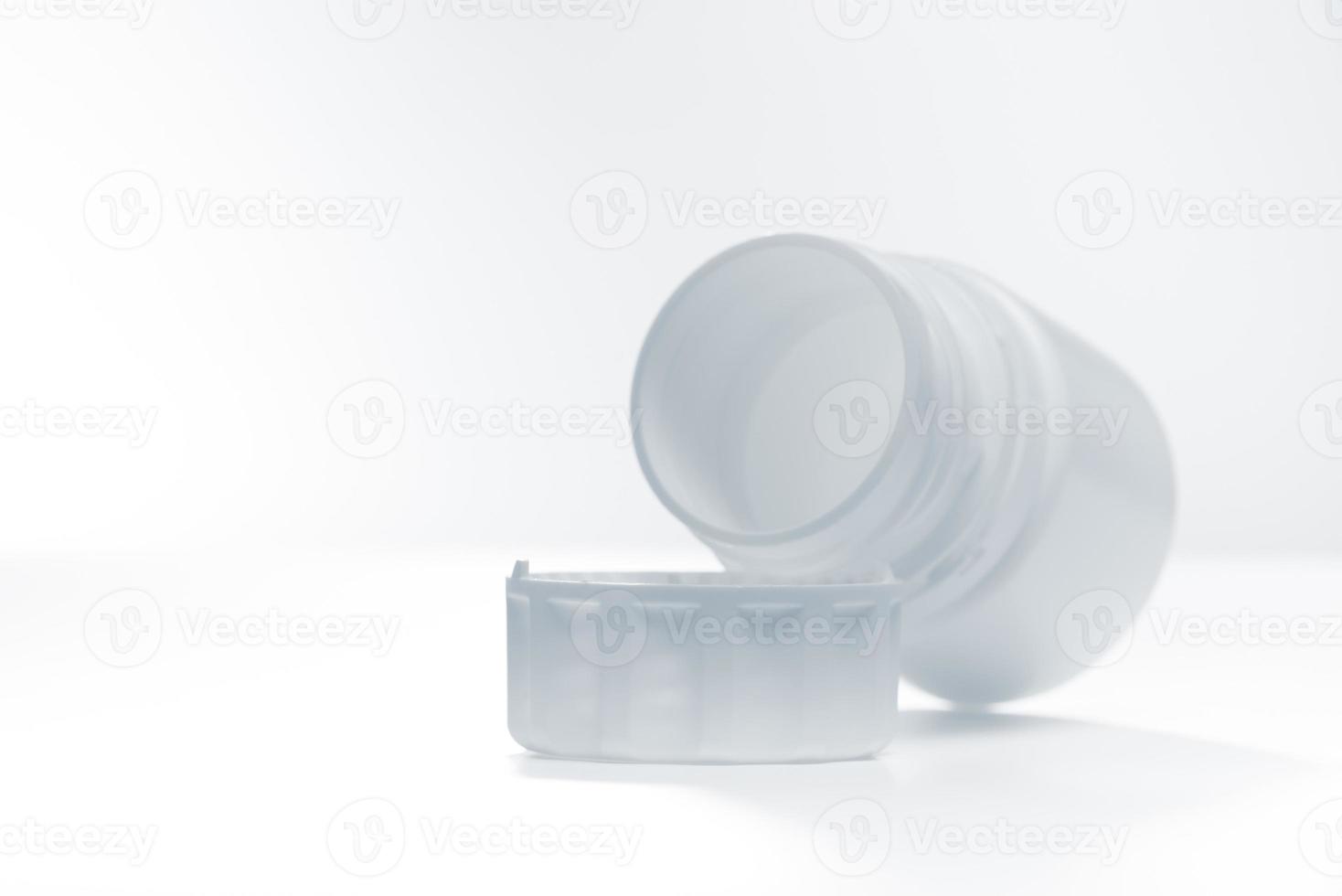 White plastic bottle lying near lid horizontally isolated on white background. Photo with copy space.