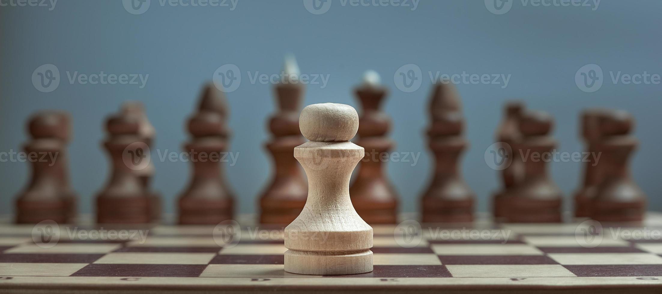 Alone against everyone, chess white pawl against opposite army on gray background. photo