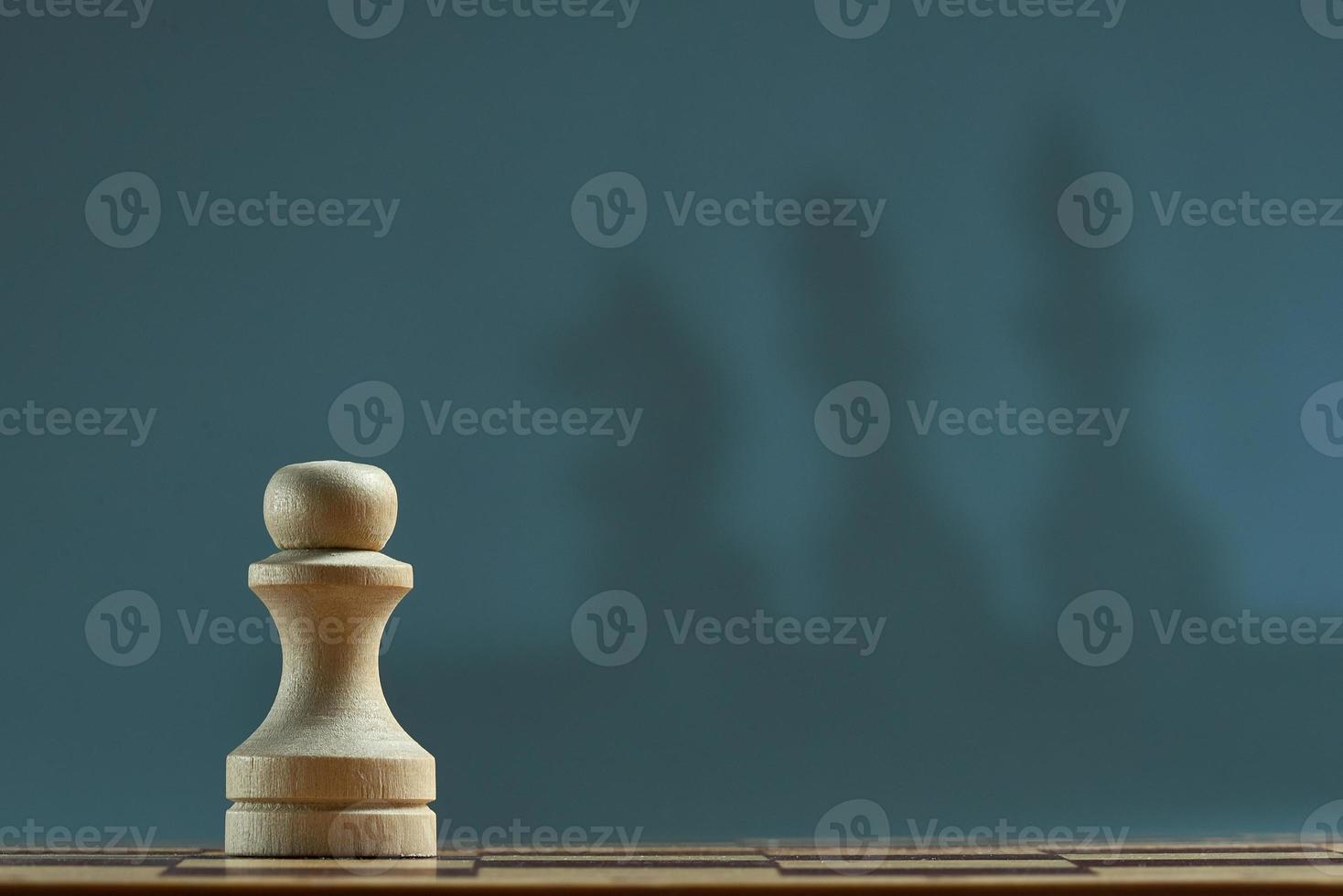 Chess pawn with blur shadow of king, Queen, horse on gray background. Photo with copy space.