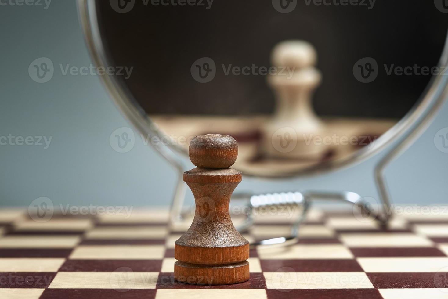 Black pawn on the background of a mirror in which the white pawn is reflected. photo