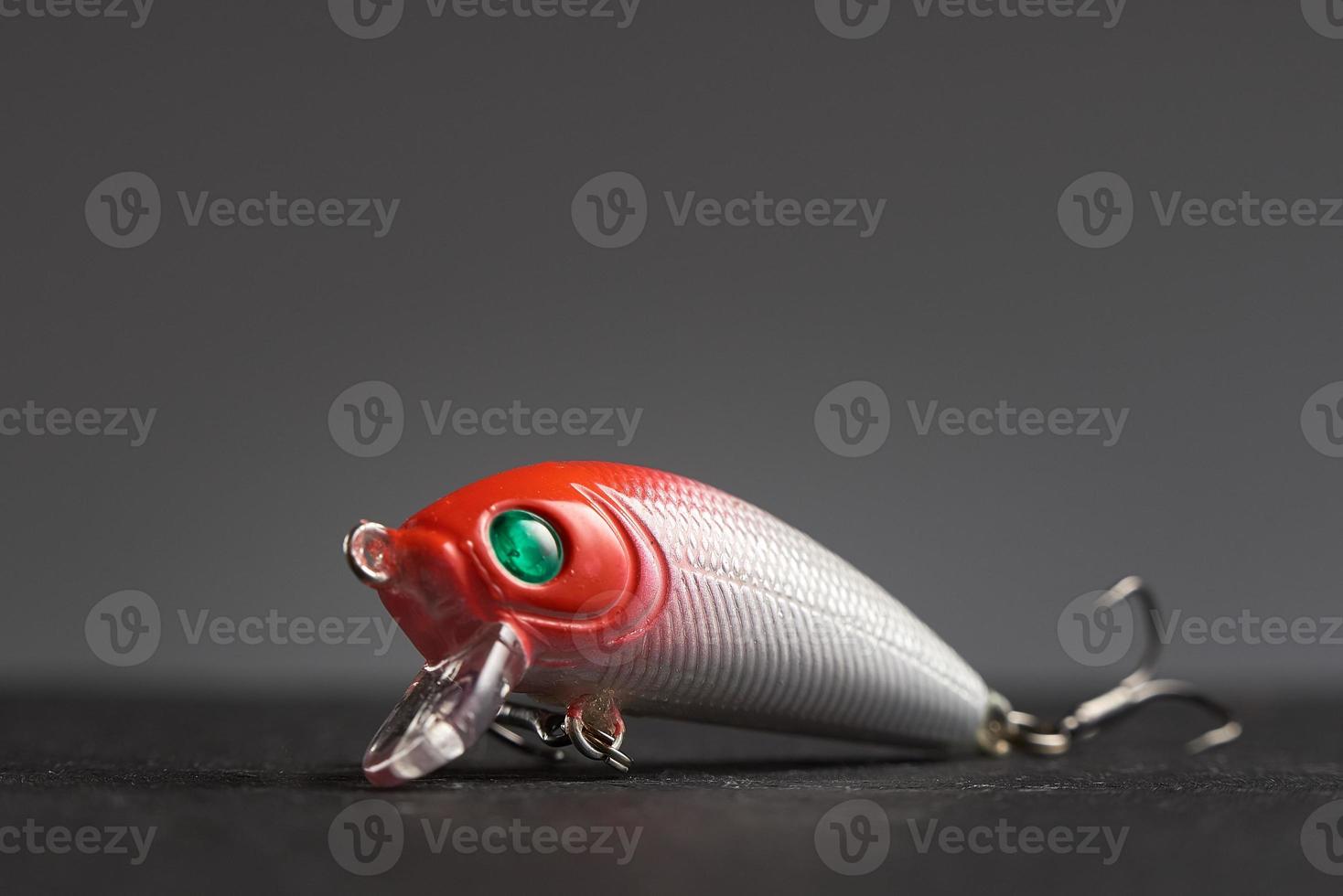 Fishing lure Wobbler closeup on gray background. Hooks and background in blur. photo