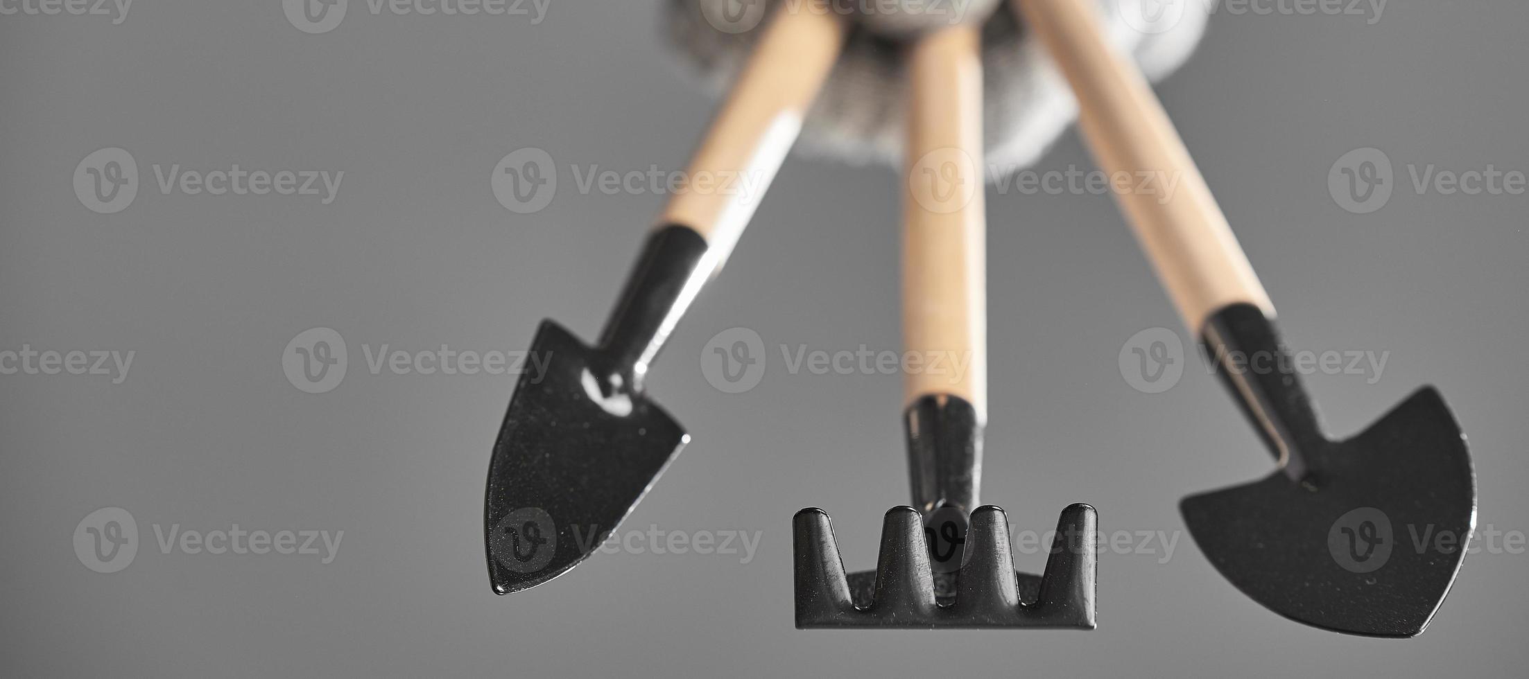 Hand in a glove holding gardening tools isolated on gray background. Photo with copy space.