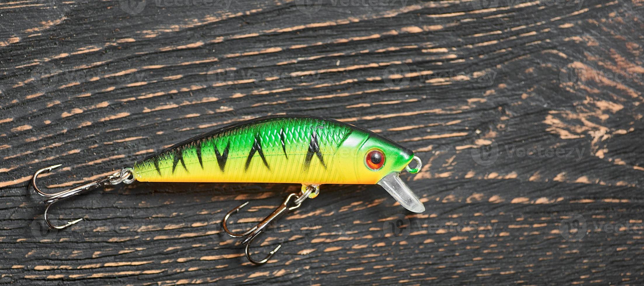 Fishing lure green Wobbler closeup on gray wooden background. photo
