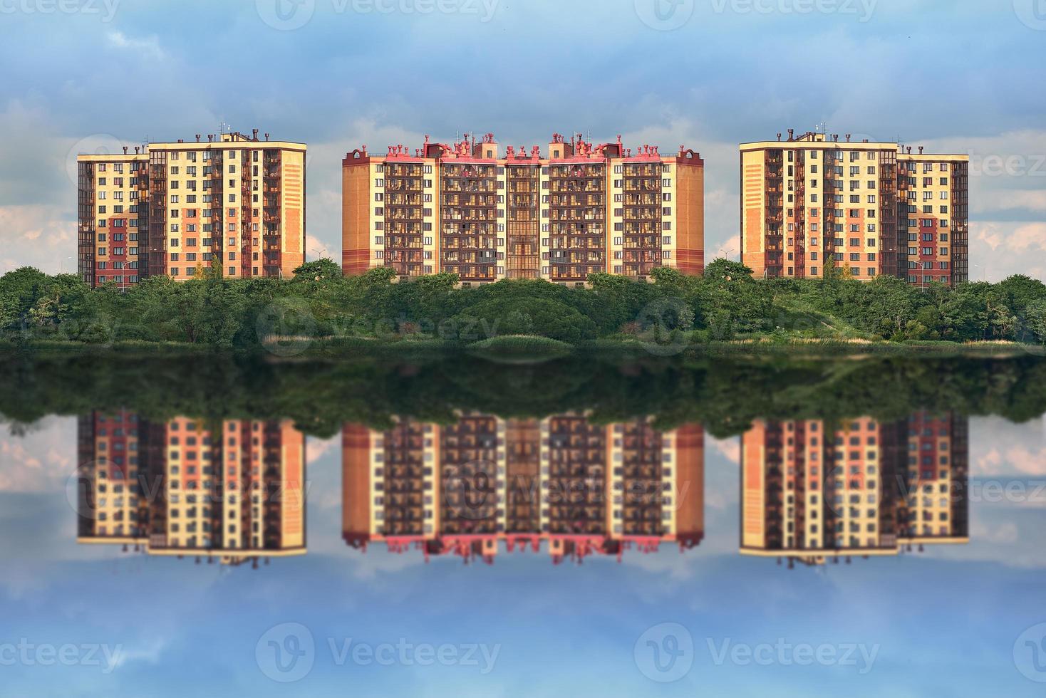 New urban area surrounded by a green Park. Symmetrical new buildings are reflected in the river. photo