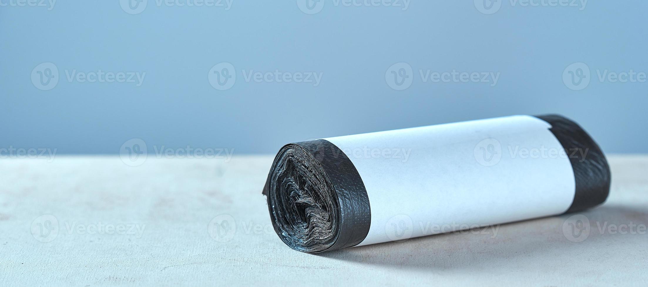 Roll black garbage bags with copy space on grey background. photo