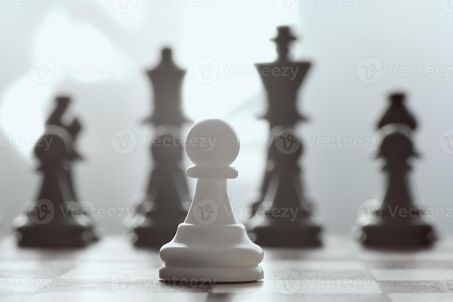 Alone against everyone, chess white pawl against opposite army on gray background. photo