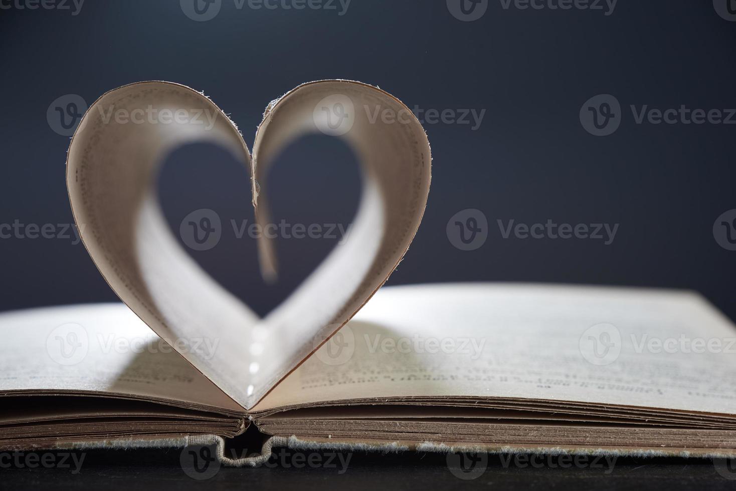 A Romance Novel. Open book close. The pages are arranged in a heart shape on a gray background in a blur. Photo with copy space.