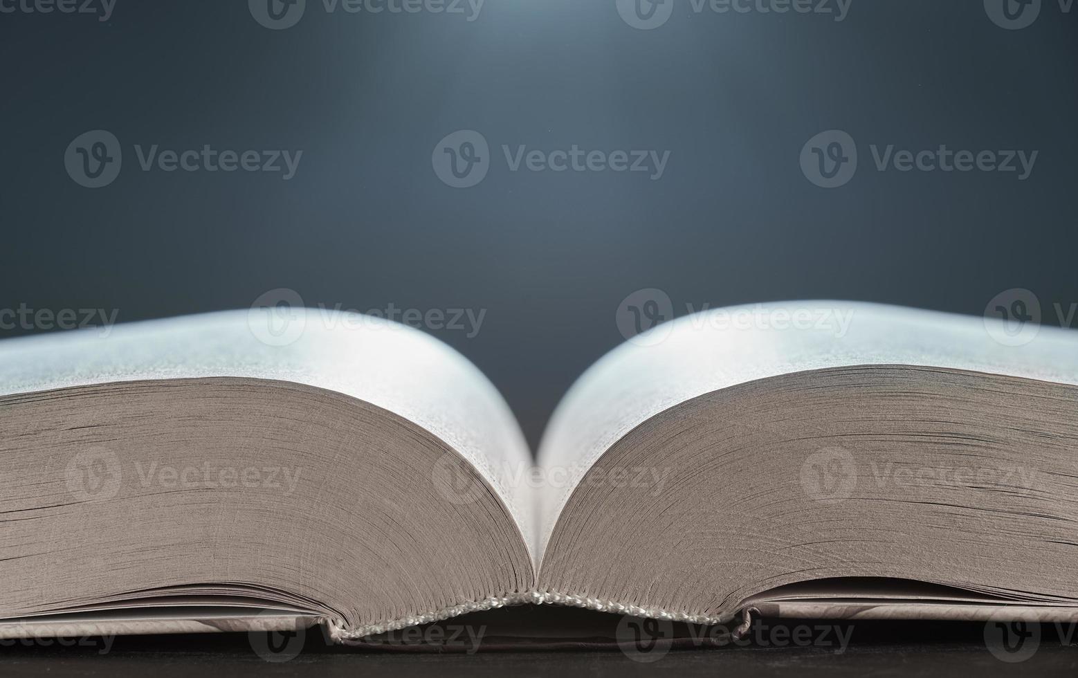 Open book illuminated by light side view close-up on a gray background. The background in blur. photo