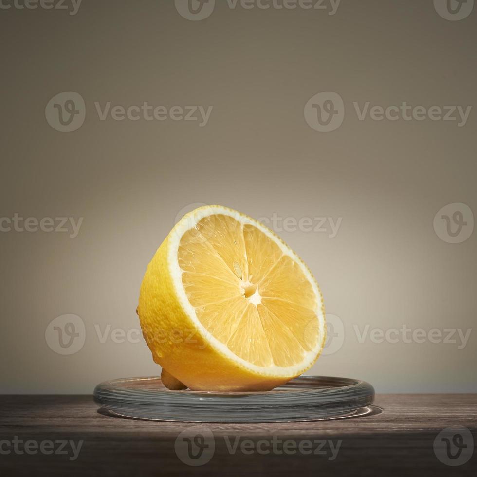 Lemon sliced in half lying on glass stand. Place for text. photo