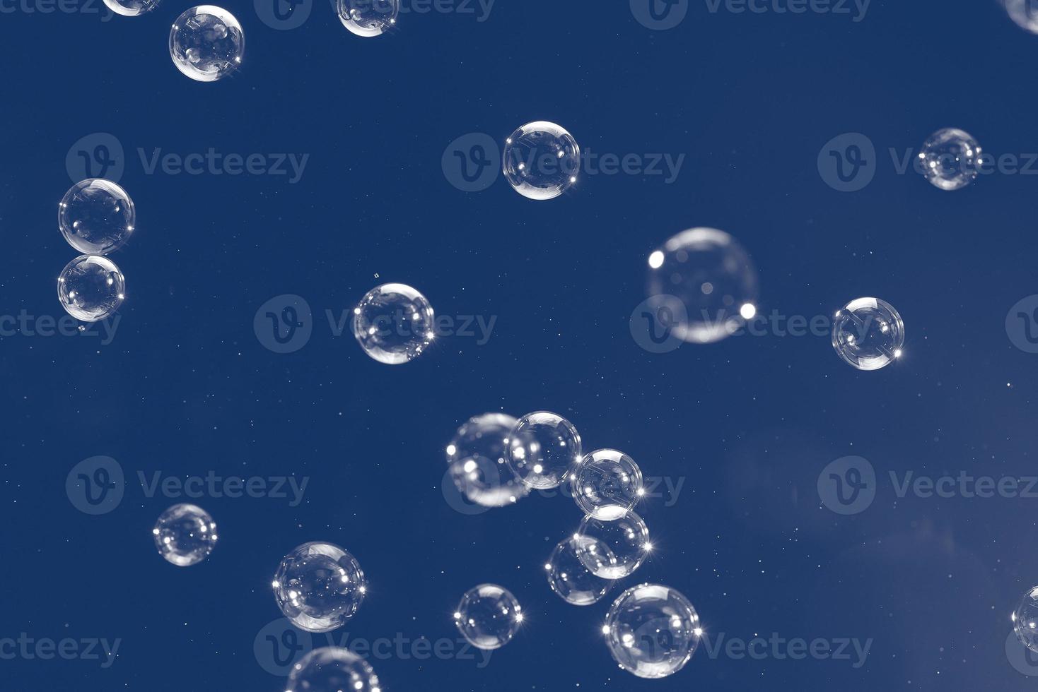 Flying soap bubbles isolated on blue background. Abstract background. photo