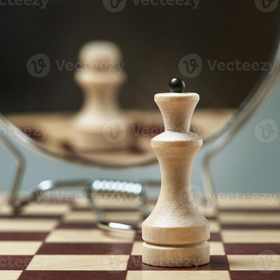 White Queen on the background of a mirror in which the white pawn is reflected. Background in blur. photo