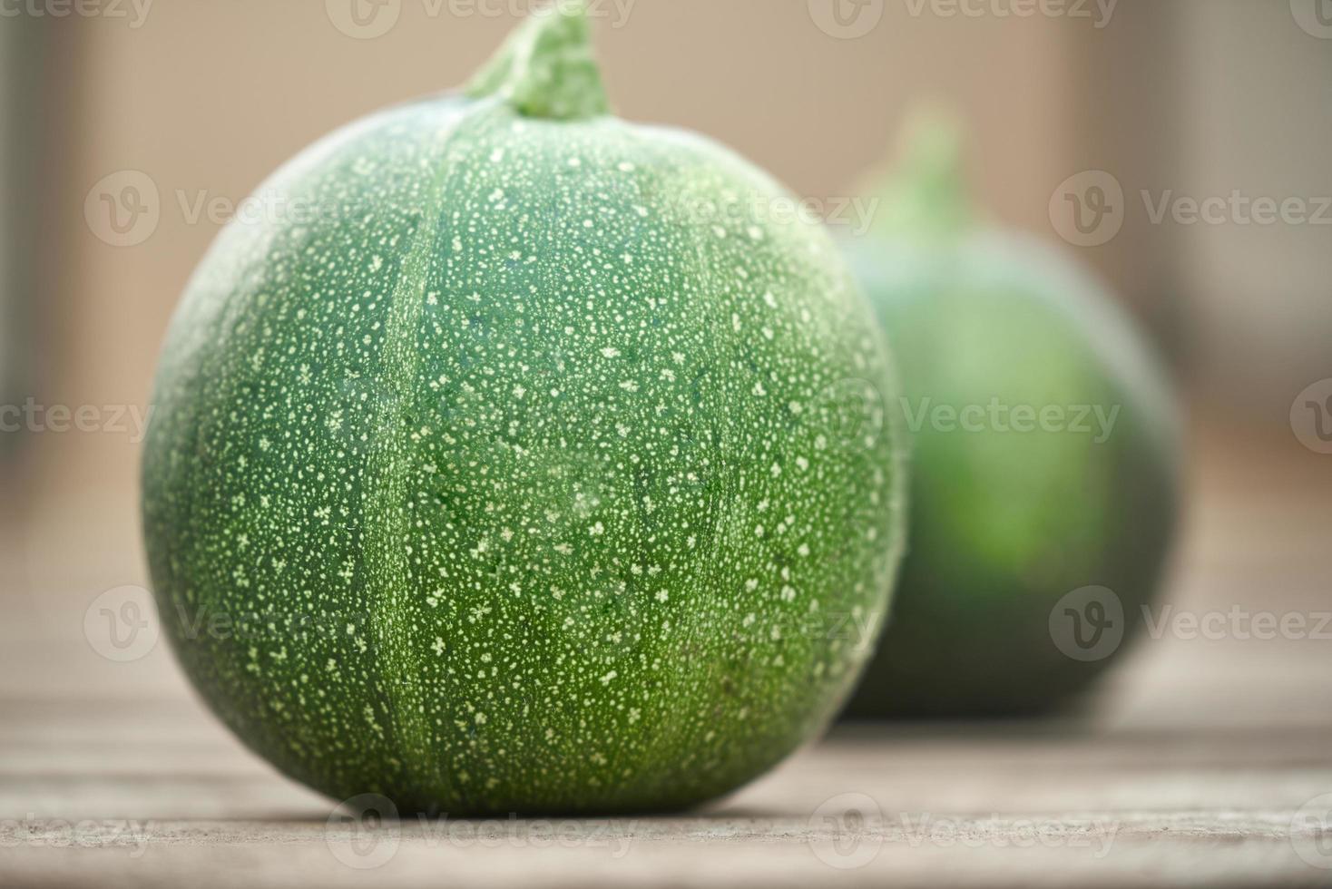 Small green zucchini on the background of vegetable marrow in a blur. photo