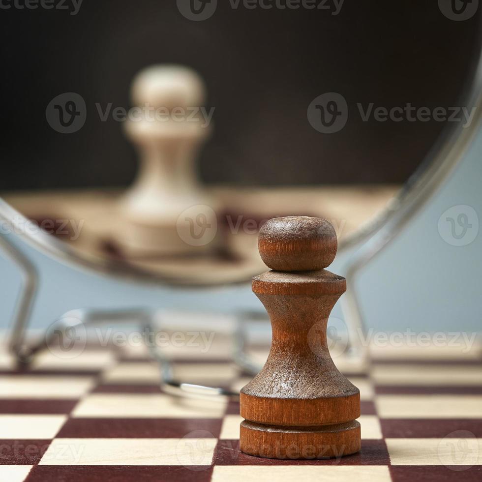 Black pawn on the background of a mirror in which the white pawn is reflected. Background in blur. photo