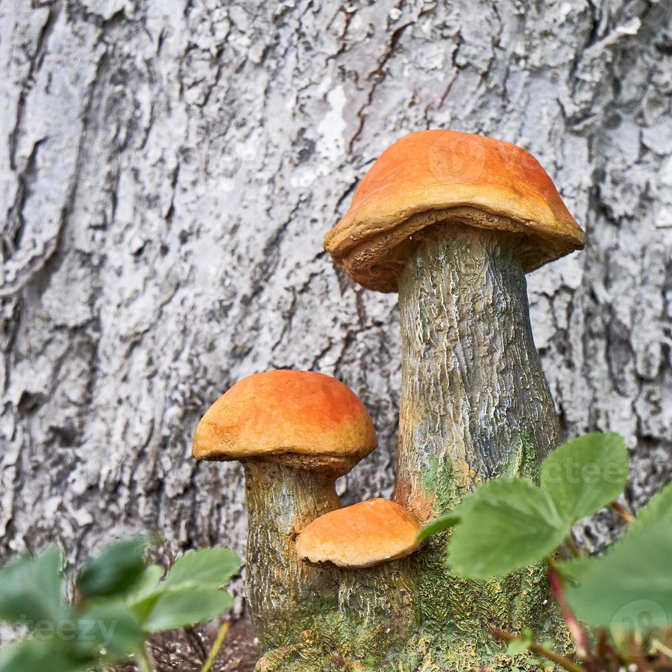 Garden statues mushrooms on the background of a tree trunk. photo
