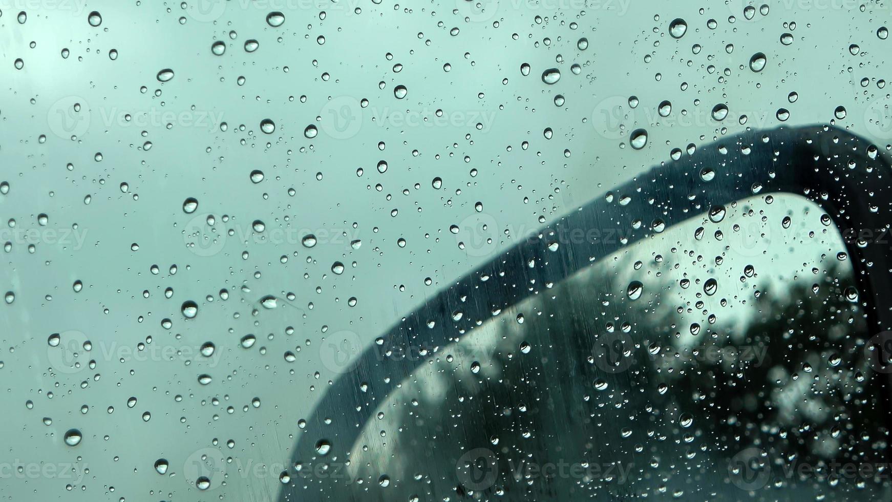 gotas de lluvia corriendo por la ventana de un auto en una vista cercana. foto