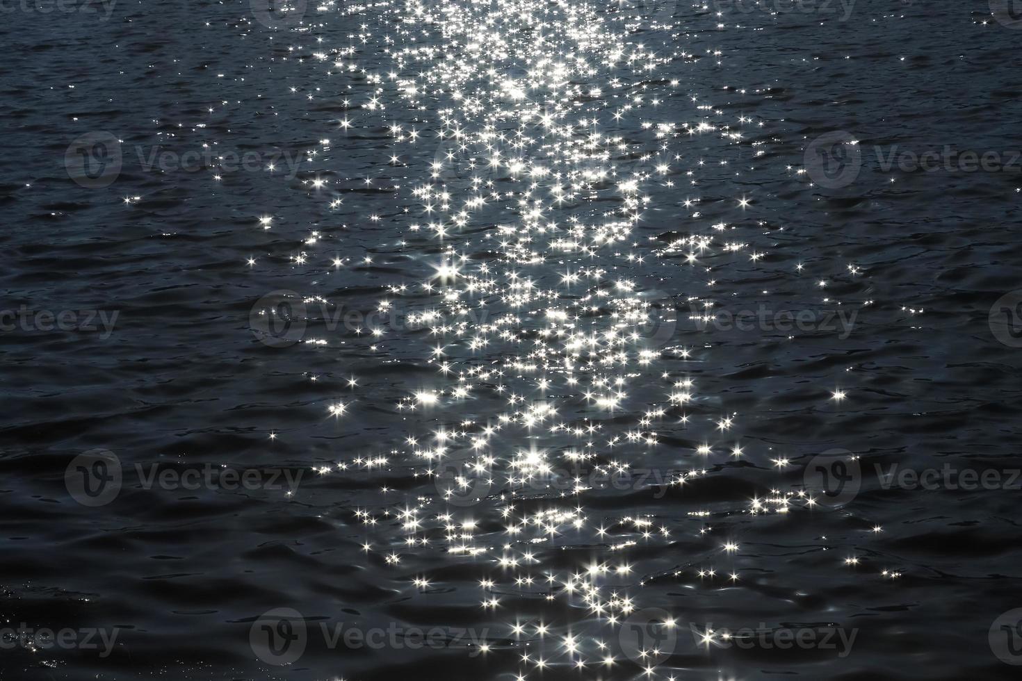 Selective focus of sparkling water with wave motion reflecting the bright sunlight with a very soft bokeh photo