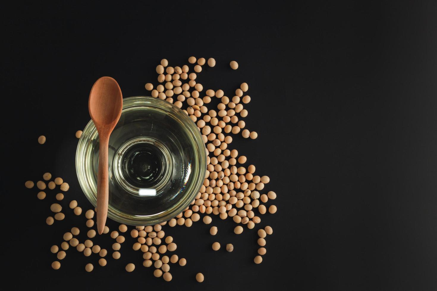 soybean in a spoon and bowl with oil on black background, top view, flat lay, top-down, selective focus.copy space. photo