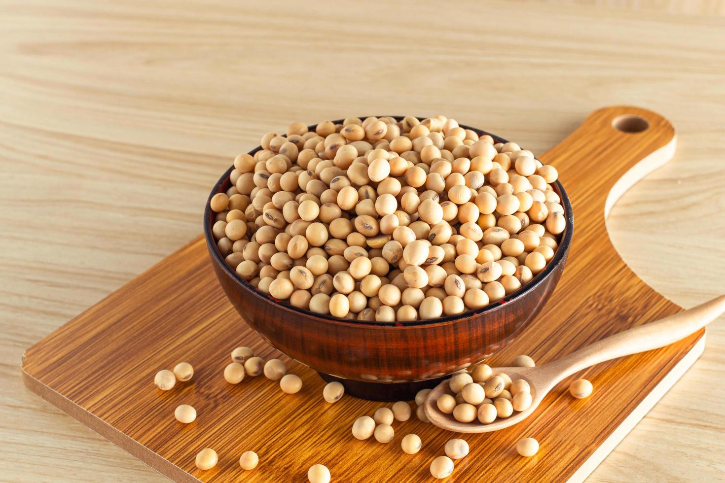 soybean in a bowl with wooden chopping board and spoon on wooden background, front view, selective focus. photo