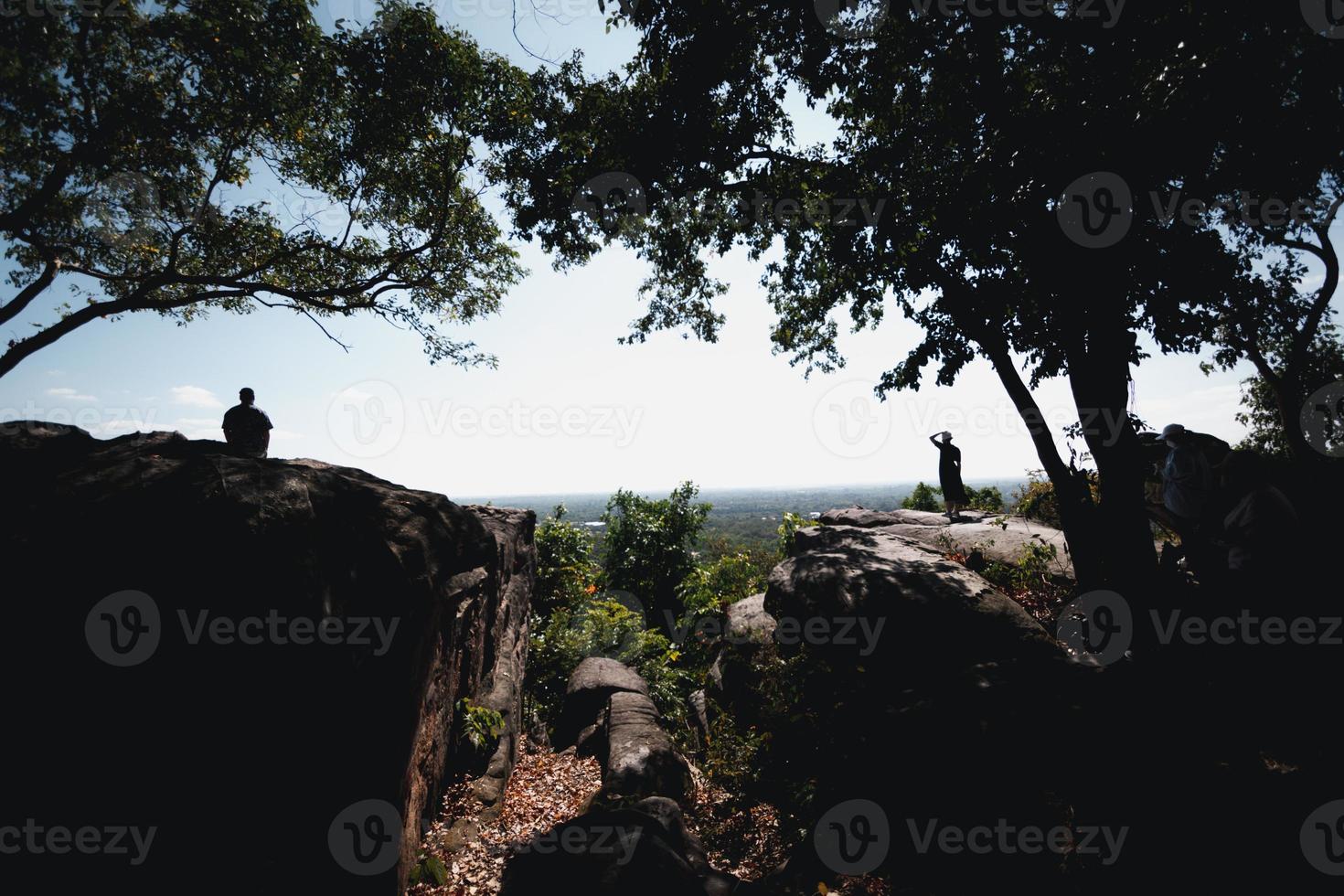 Wide angle silhouette of the scenery on the cliffs and trees overlooking the countryside below, with tourists standing behind their backs, the concept of natural relaxation tourism. photo