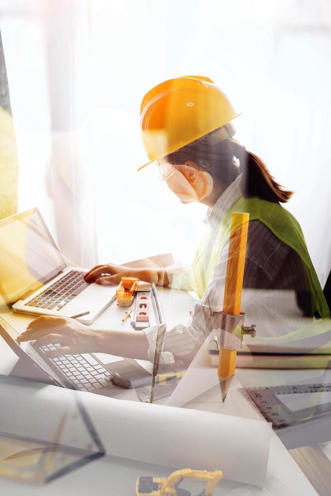 Two colleagues discussing data working and tablet, laptop with on on architectural project at construction site at desk in office photo