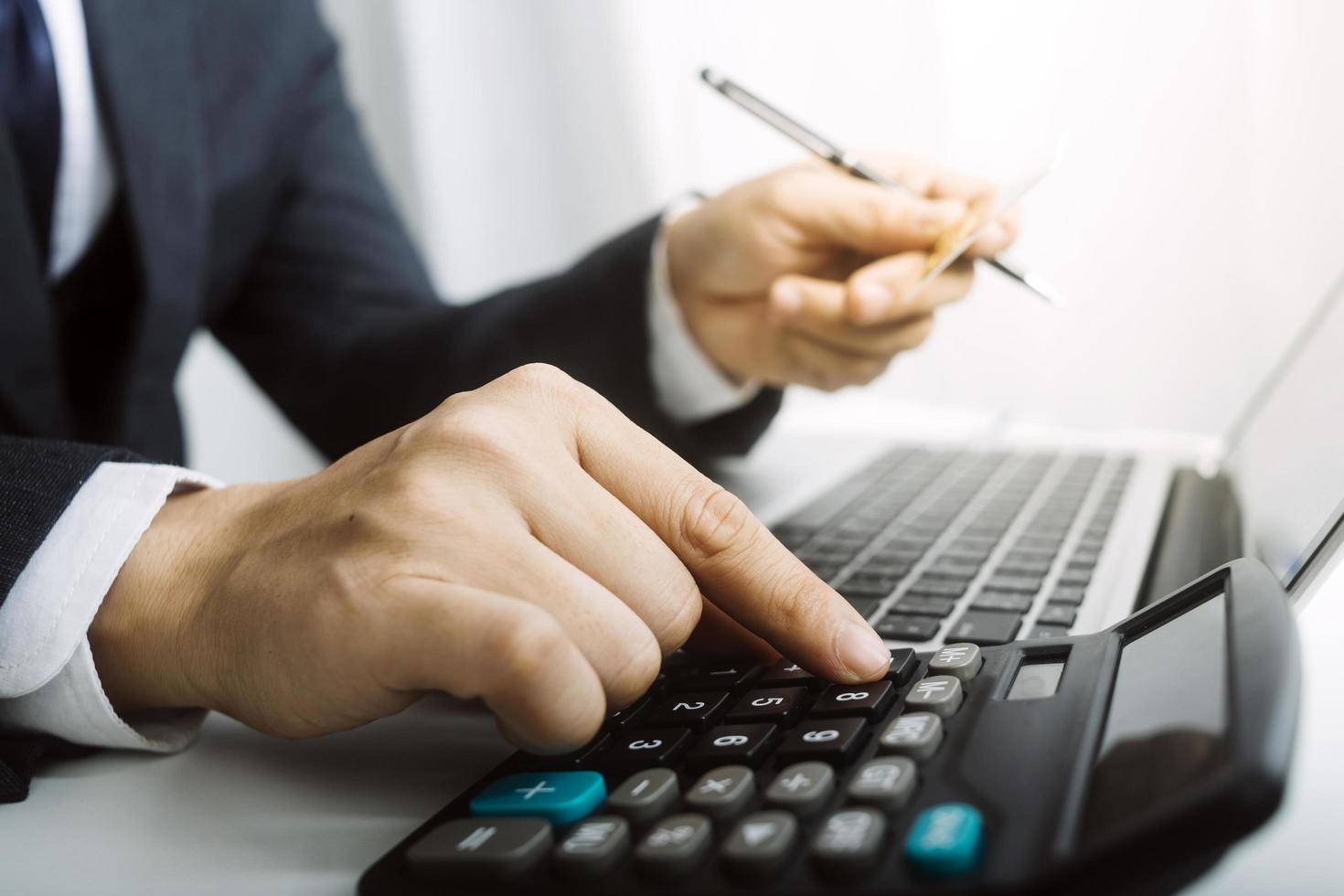 Business accounting concept, Business man using calculator with computer laptop, budget and loan paper in office. photo