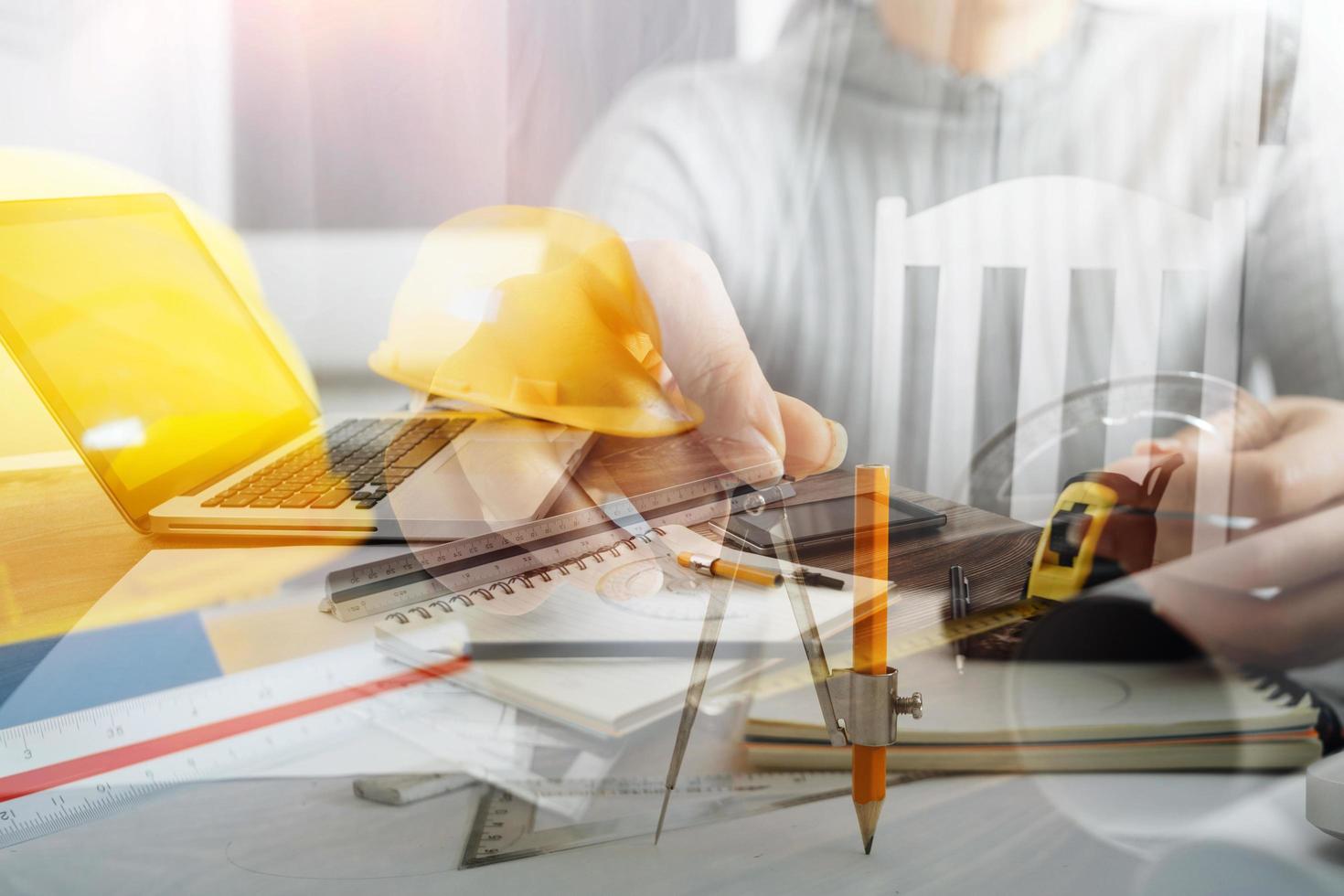 Two colleagues discussing data working and tablet, laptop with on on architectural project at construction site at desk in office photo