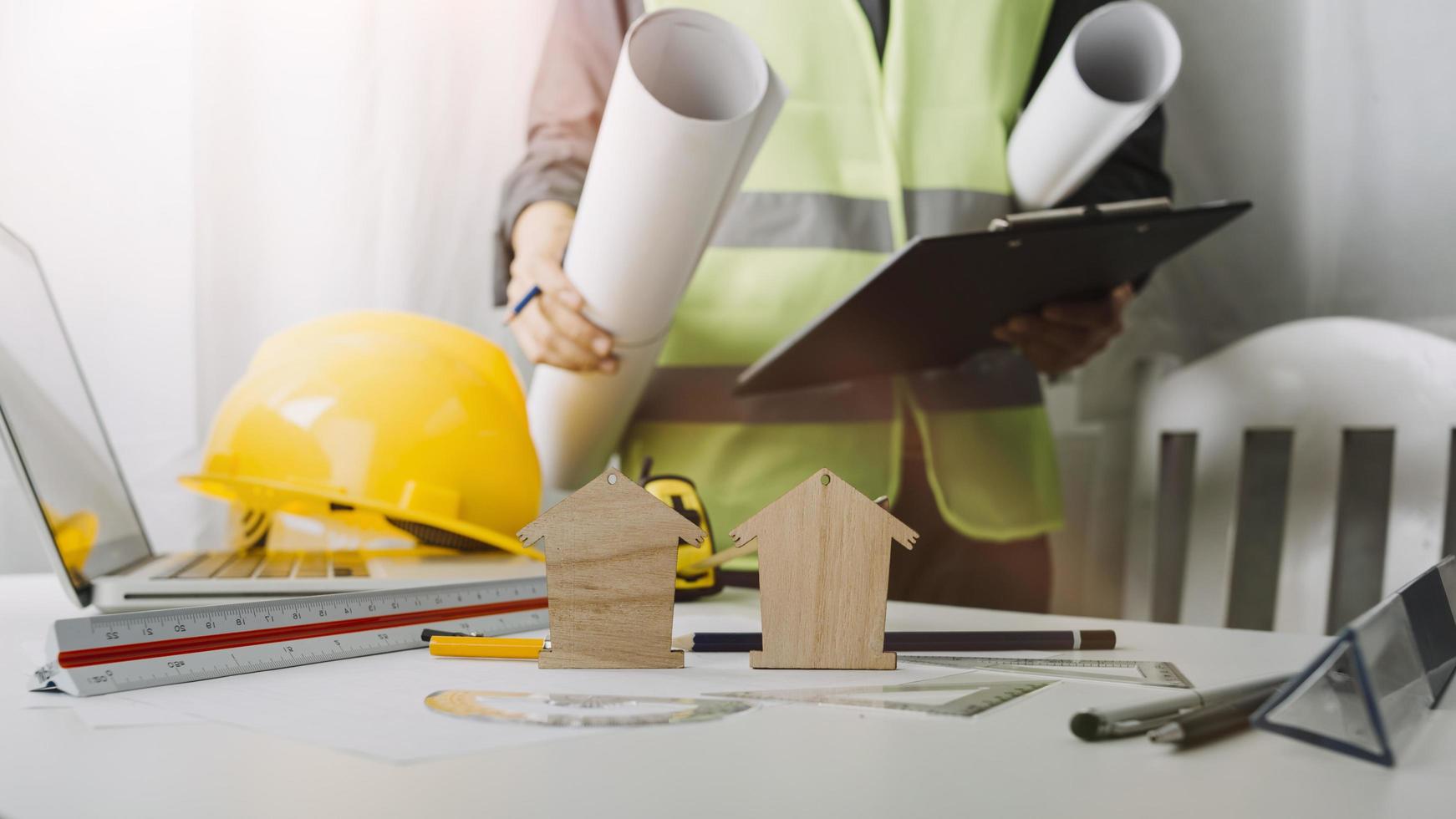 Two colleagues discussing data working and tablet, laptop with on on architectural project at construction site at desk in office photo