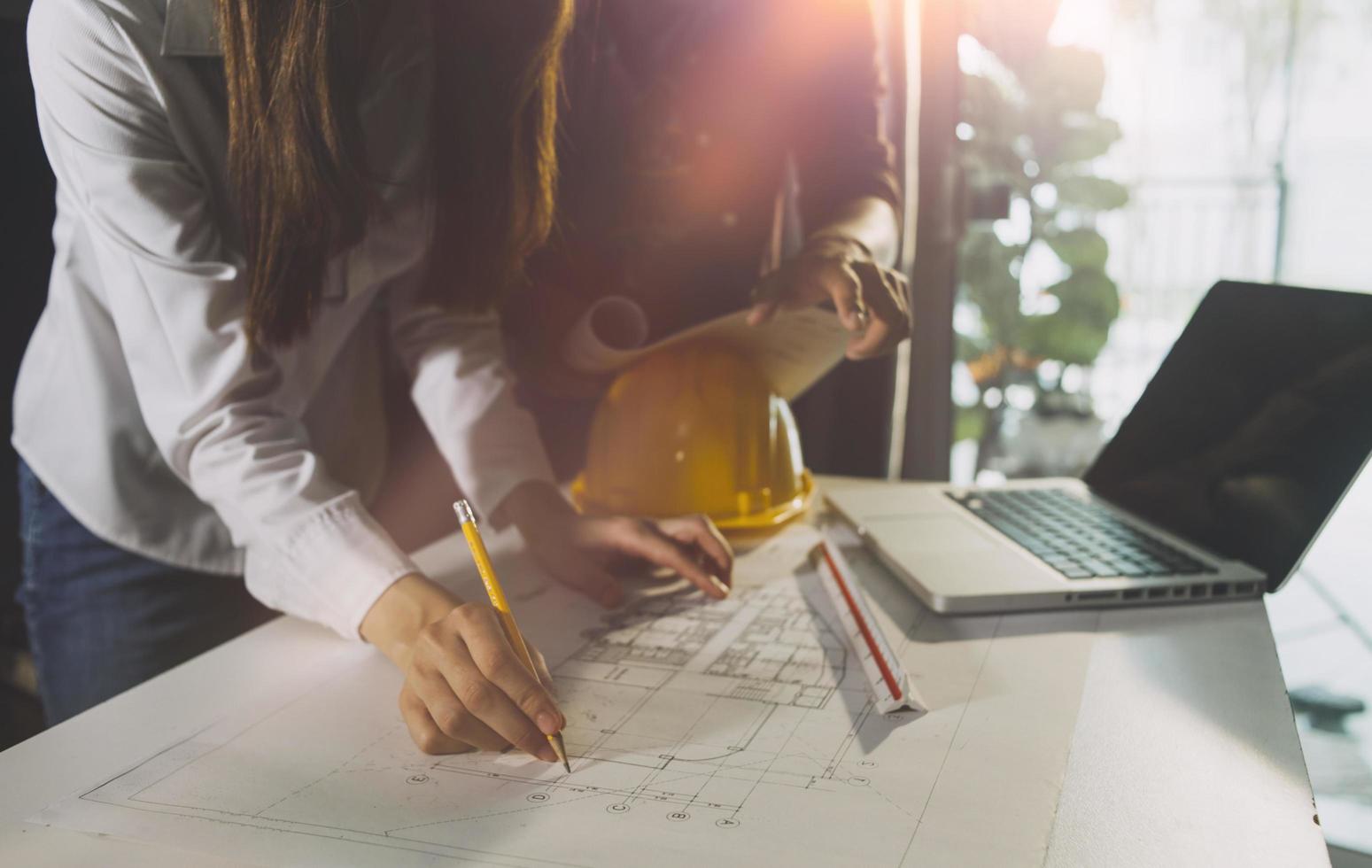 trabajo manual de negocios y computadora portátil con un proyecto arquitectónico en el sitio de construcción en el escritorio de la oficina foto