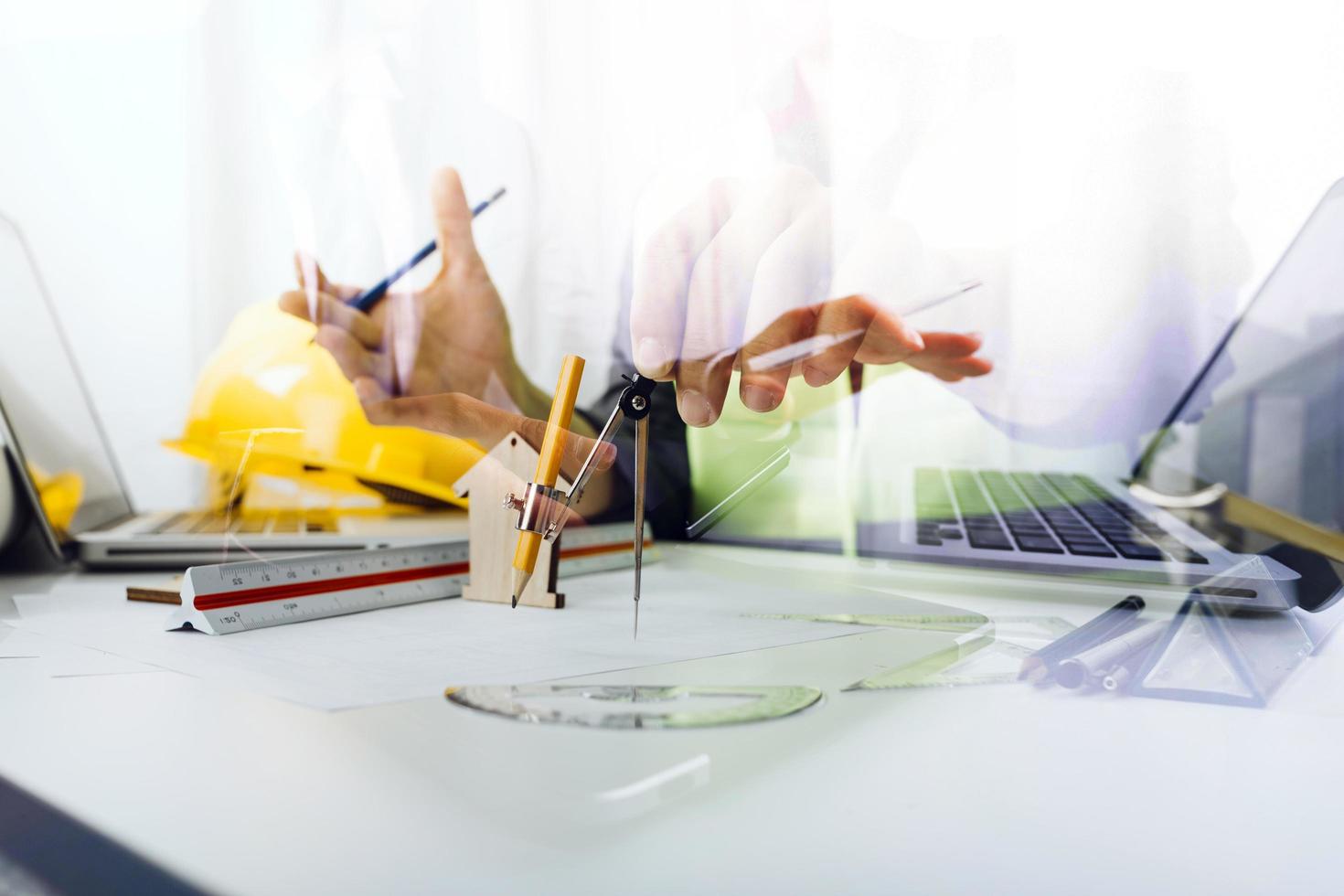 trabajo manual de negocios y computadora portátil con un proyecto arquitectónico en el sitio de construcción en el escritorio de la oficina foto