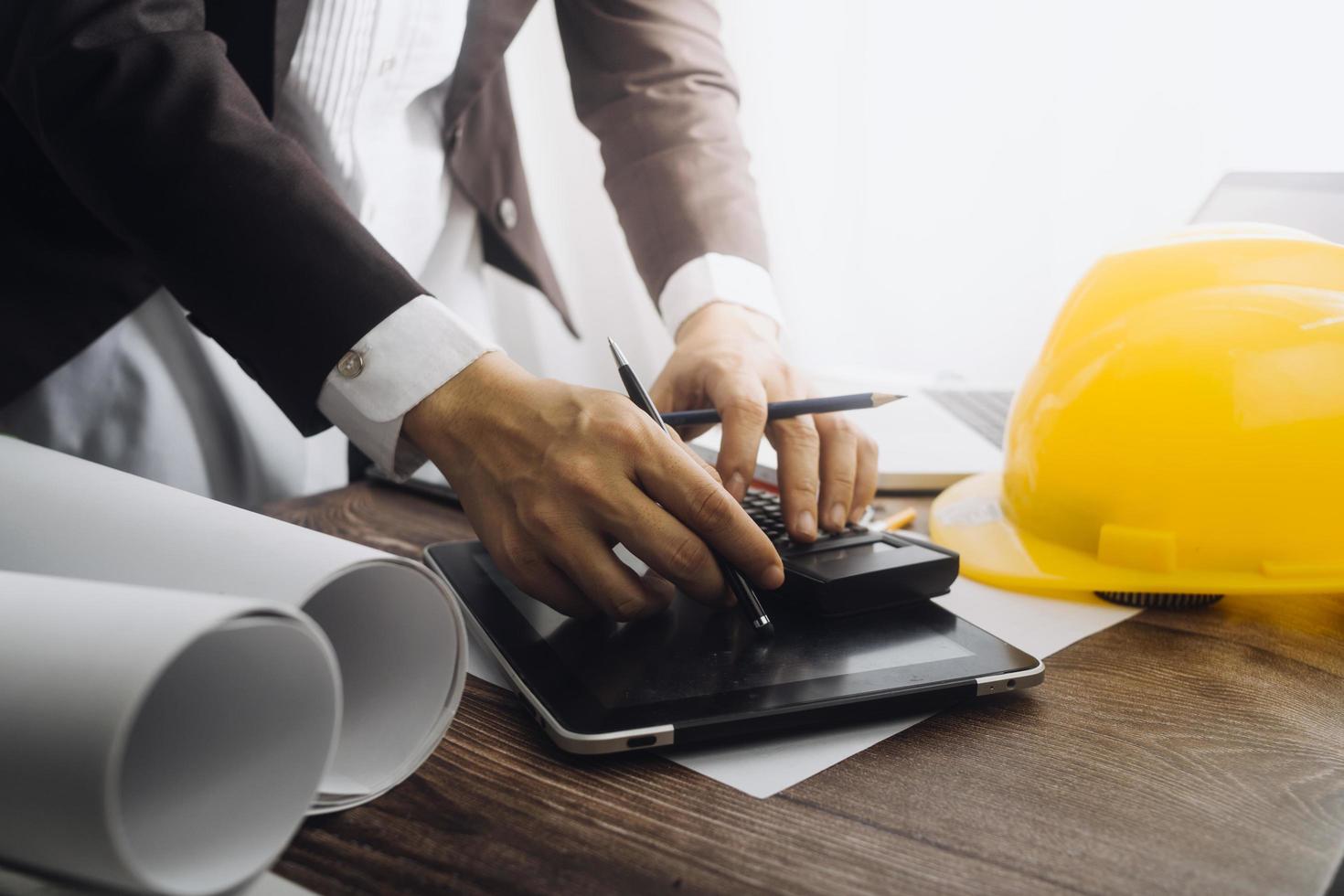 Two colleagues discussing data working and tablet, laptop with on on architectural project at construction site at desk in office photo