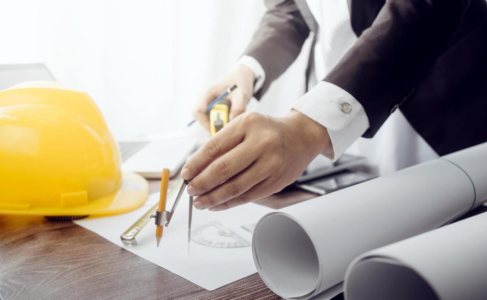 Two colleagues discussing data working and tablet, laptop with on on architectural project at construction site at desk in office photo